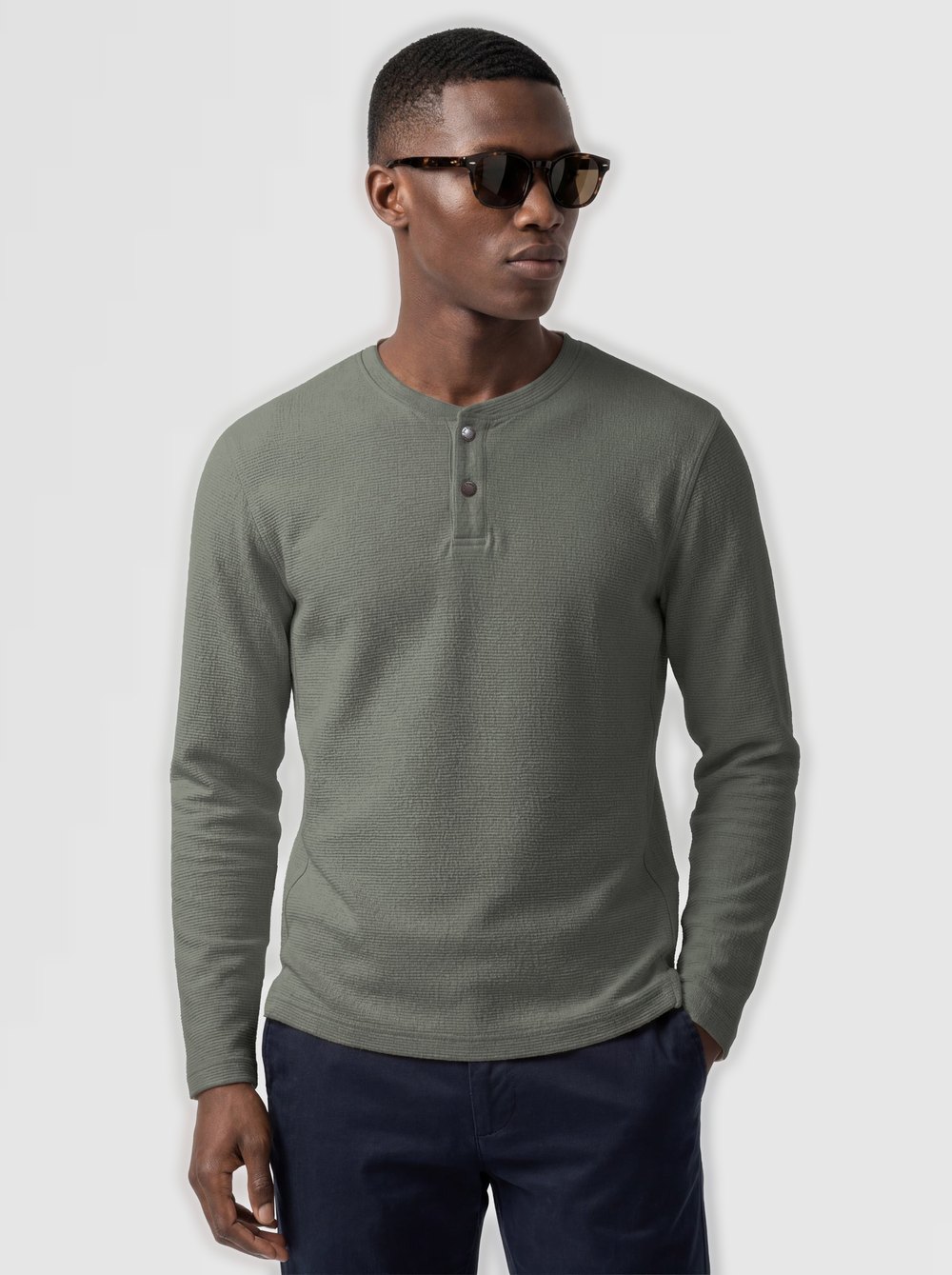 Man in a moss waffle-knit henley and navy trousers